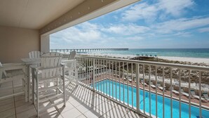 Een balkon met uitzicht op een strand, een pier en een zwembad.