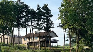 A house with a large deck, surrounded by tall trees and a grassy field. - Beautiful house on Lake Rathbun with in-ground pool & 50-amp camper hookup (Plano)