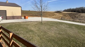 A building with a garage, a tree, and a gravel driveway. - Beautiful house on Lake Rathbun with in-ground pool & 50-amp camper hookup (Plano)