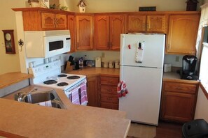 Kitchen area with stove, microwave, refrigerator, sink, and various kitchen utensils.