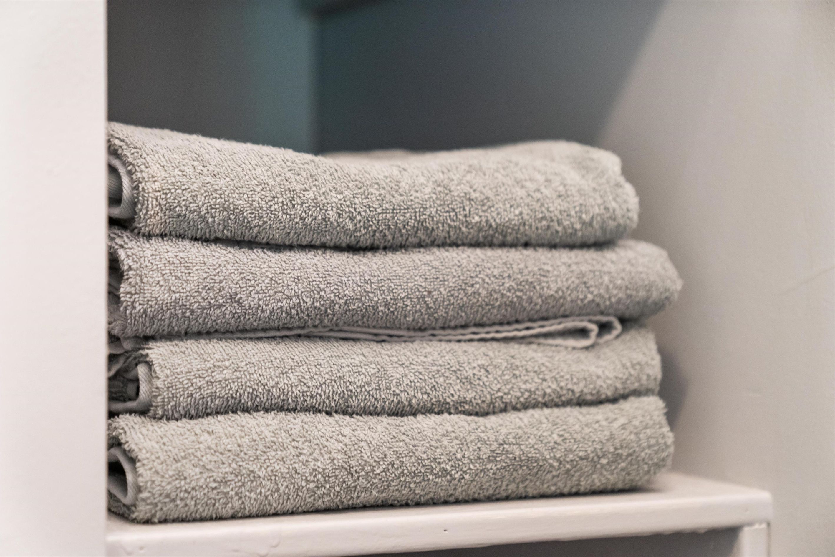 A stack of folded towels on a white shelf.