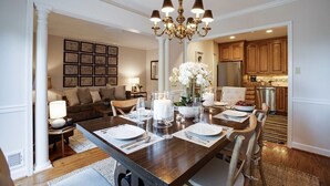 Un comedor con una mesa de madera dispuesta para cuatro personas, rodeada de sillas, una araña y cuadros en la pared.