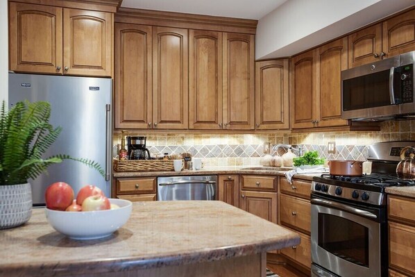 A kitchen with wooden cabinets, stainless steel appliances, and a granite countertop.