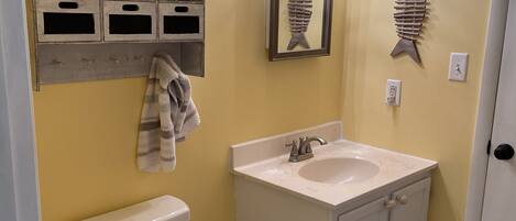 Une salle de bain équipée de toilettes, d’un lavabo et d’une étagère où sont disposés des objets décoratifs.