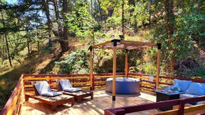 Une terrasse en bois avec des sièges d’extérieur, une balançoire et un auvent.