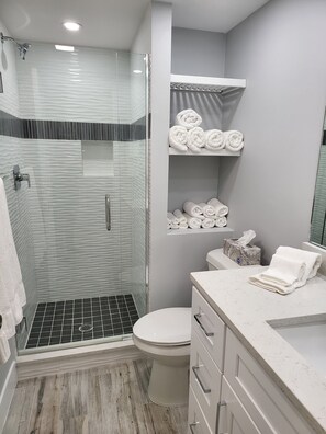 Ein modernes Badezimmer mit einer Duschkabine, einer Toilette und einem Waschtisch mit Handtuchhalter.