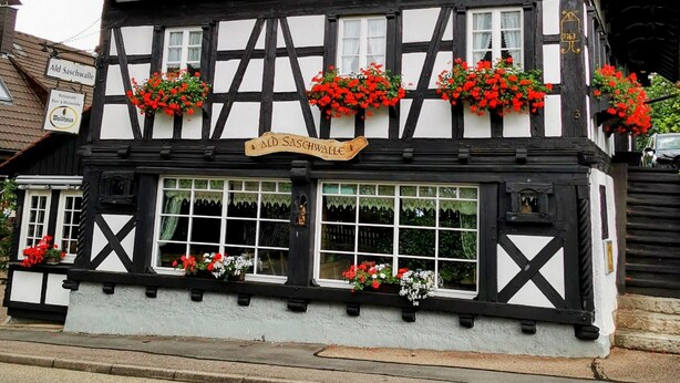 A traditional half-timbered building with multiple windows and flower boxes. - Romantic modern Black Forest loft | Netflix | WiFi | free public transport (Sasbachwalden)