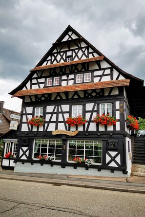 Edifici tradicional amb estructura de fusta i estuc, amb diverses finestres i balcons florals.
