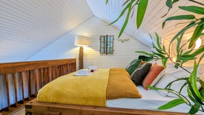 A cozy, wooden-framed bed with a yellow blanket, a white pillow, and a green plant beside it. - Romantic modern Black Forest loft | Netflix | WiFi | free public transport (Sasbachwalden)
