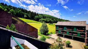 A building with a green roof, a parking garage, and a view of a green field and forest. - Romantic modern Black Forest loft | Netflix | WiFi | free public transport (Sasbachwalden)