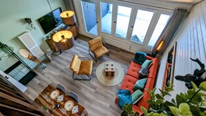 A spacious living area with a sofa, chairs, a dining table, and a TV. - Romantic modern Black Forest loft | Netflix | WiFi | free public transport (Sasbachwalden)