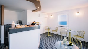 A modern kitchen with a central island, a dining area with yellow chairs, and a view of the sea through a window. - La Vigna di Bacco (Furore)