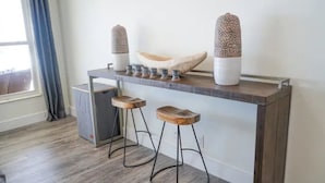 Une cuisine moderne avec un plan de travail en bois, deux tabourets et des objets décoratifs.