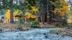 Un río serpenteando por un bosque con cabañas de madera.