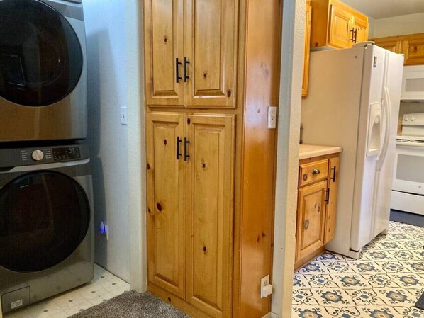 Une cuisine avec des meubles en bois, un lave-linge, un réfrigérateur et un sol à motifs.