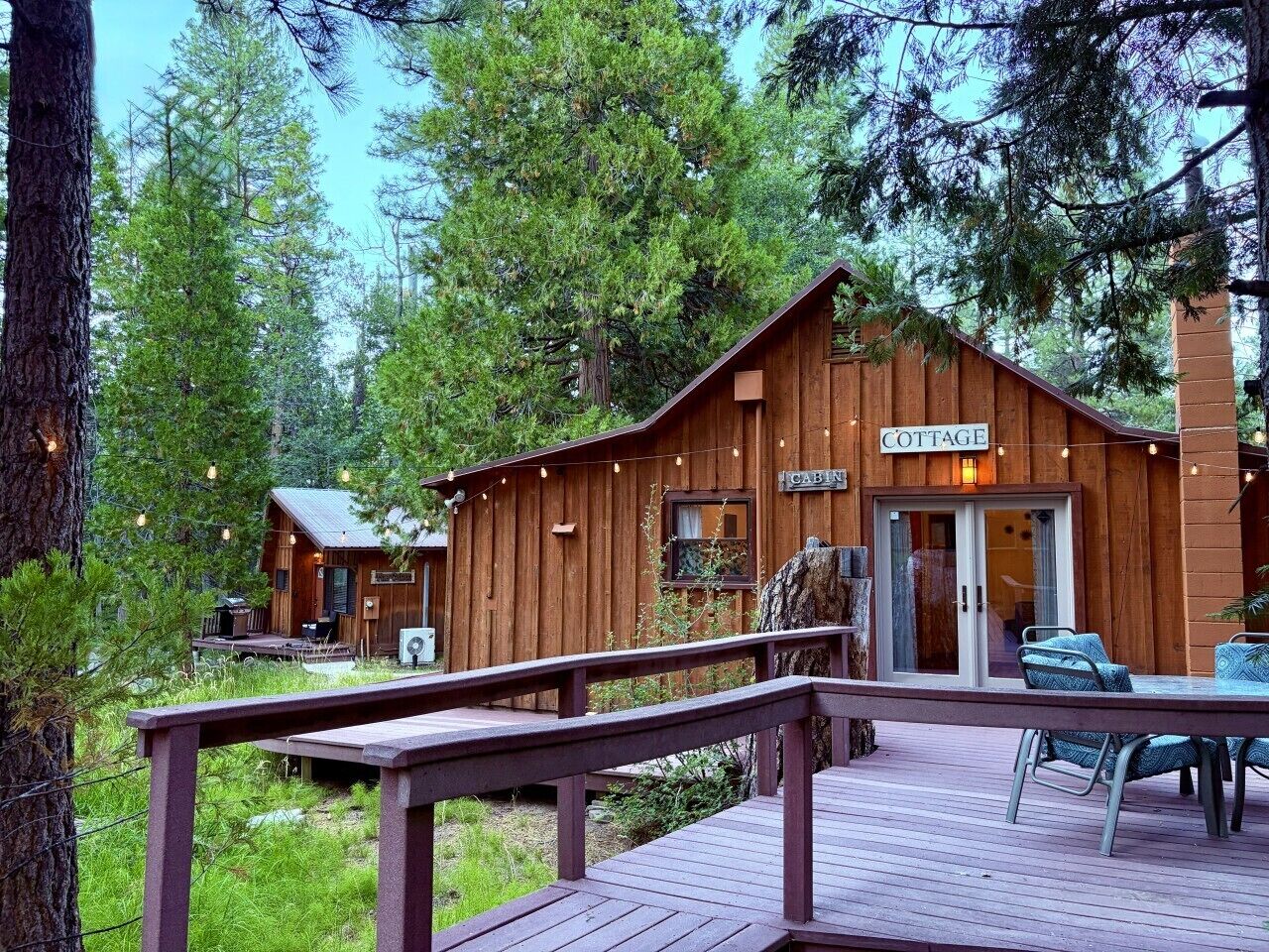A wooden cabin labeled 'COTTAGE' with a deck and outdoor seating.