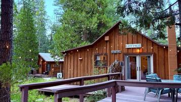 A wooden cabin labeled 'COTTAGE' with a deck and outdoor seating.
