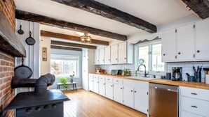 Una cocina moderna con armarios blancos, encimera de madera y estufa negra.