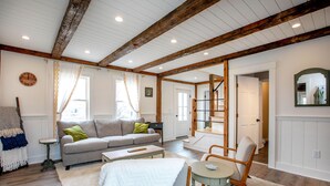 Una sala de estar con sofá, sillones, una mesa de centro y una escalera que lleva a otra habitación.