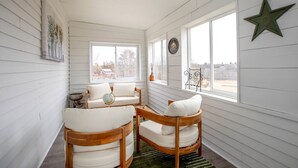 Un cuarto acogedor con paredes de madera blanca, una decoración de estrella, un globo en una silla y vistas a través de amplias ventanas.