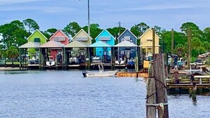 Una propiedad frente al agua con varias casas coloridas, un muelle y un poste de madera en primer plano.