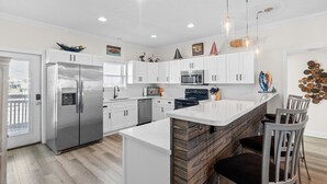 Una cocina moderna con armarios blancos, electrodomésticos de acero inoxidable y una isla central con asientos.