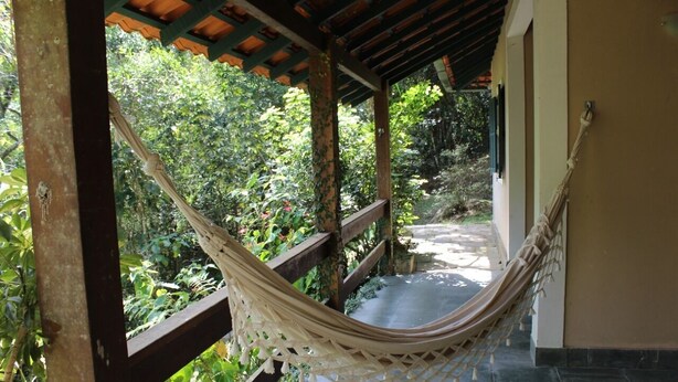 A hammock under a wooden pergola with a view of a garden path and greenery. - Casinha no sítio Calmamente  (Teresópolis)