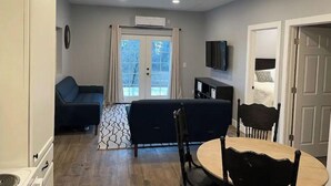 A compact living space with a sofa, a dining table, and a TV mounted on the wall. - Peaceful Escapes and Retreats (Battle Ground)