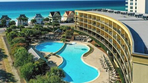 Ein Hotel mit großem Pool, Blick auf den Strand und einem mehrstöckigen Gebäude mit Balkonen.