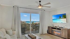 Ein modernes Wohnzimmer mit Sofa, Couchtisch, Kamin und an der Wand montiertem Fernseher.