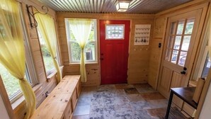 A wooden interior with a red door, a bench, and a tiled floor. - Creekfront Cabin • Fire Pit • Fenced Yard • Near Crabtree Falls (Tyro)