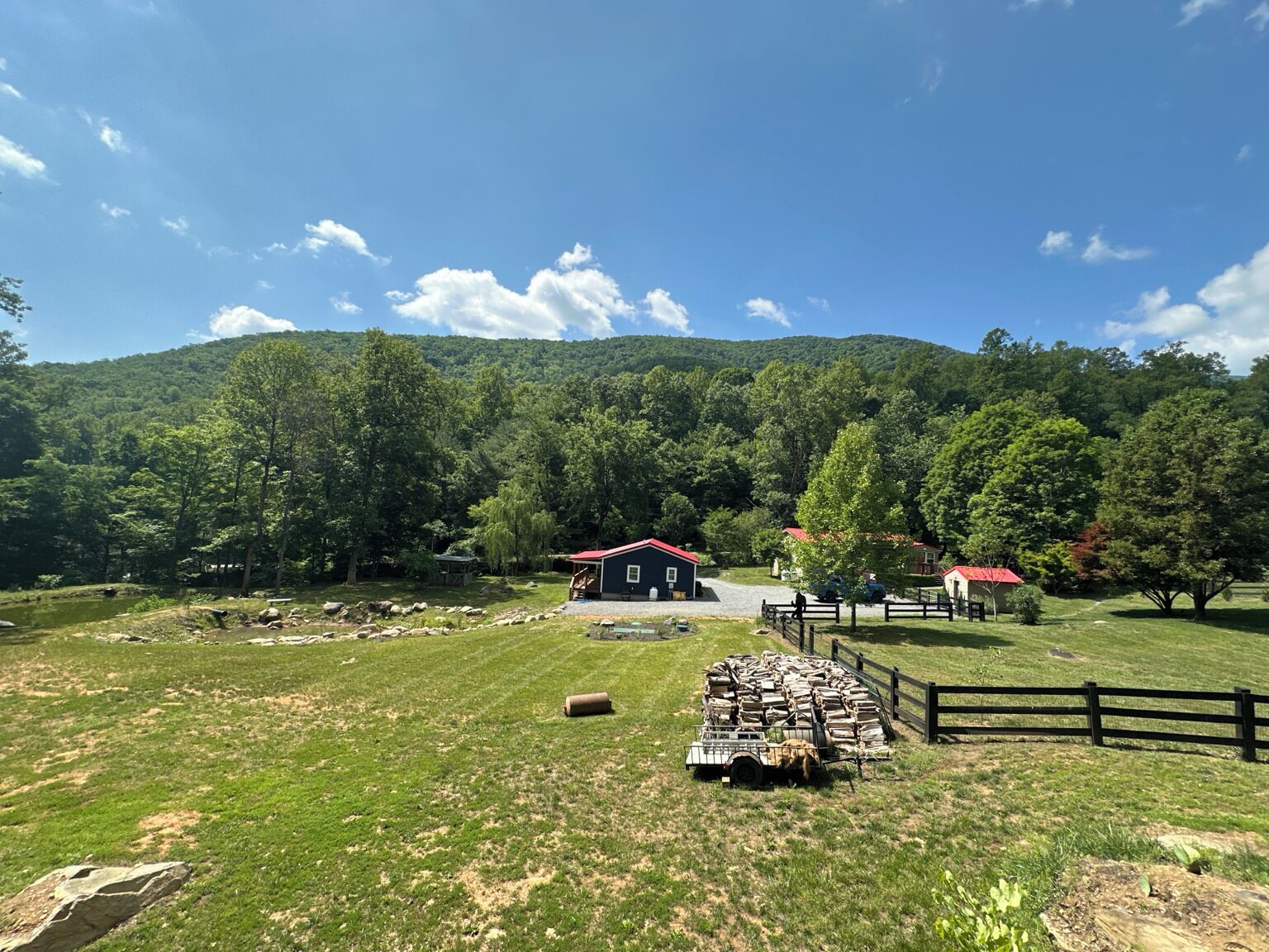 Paisatge rural amb una granja, una zona tancada amb farates, i un cel serè.