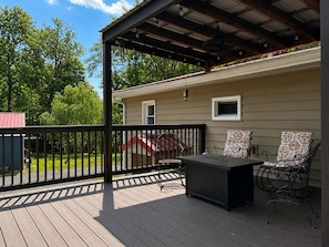 Une terrasse couverte avec une table et des chaises, un toboggan rouge et une maison en arrière-plan.