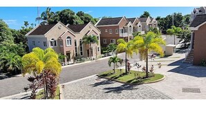 Une rue résidentielle bordée de maisons, avec une chaussée goudronnée et de petits arbres.