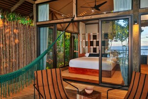 Un dormitorio con una cama grande, una hamaca y vistas al exterior.