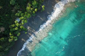 Vista aérea de una zona costera con aguas turquesas cristalinas, vegetación verde exuberante y un litoral rocoso.