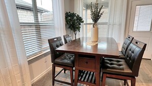 Comedor con una mesa de madera, seis sillas y un florero con flores.