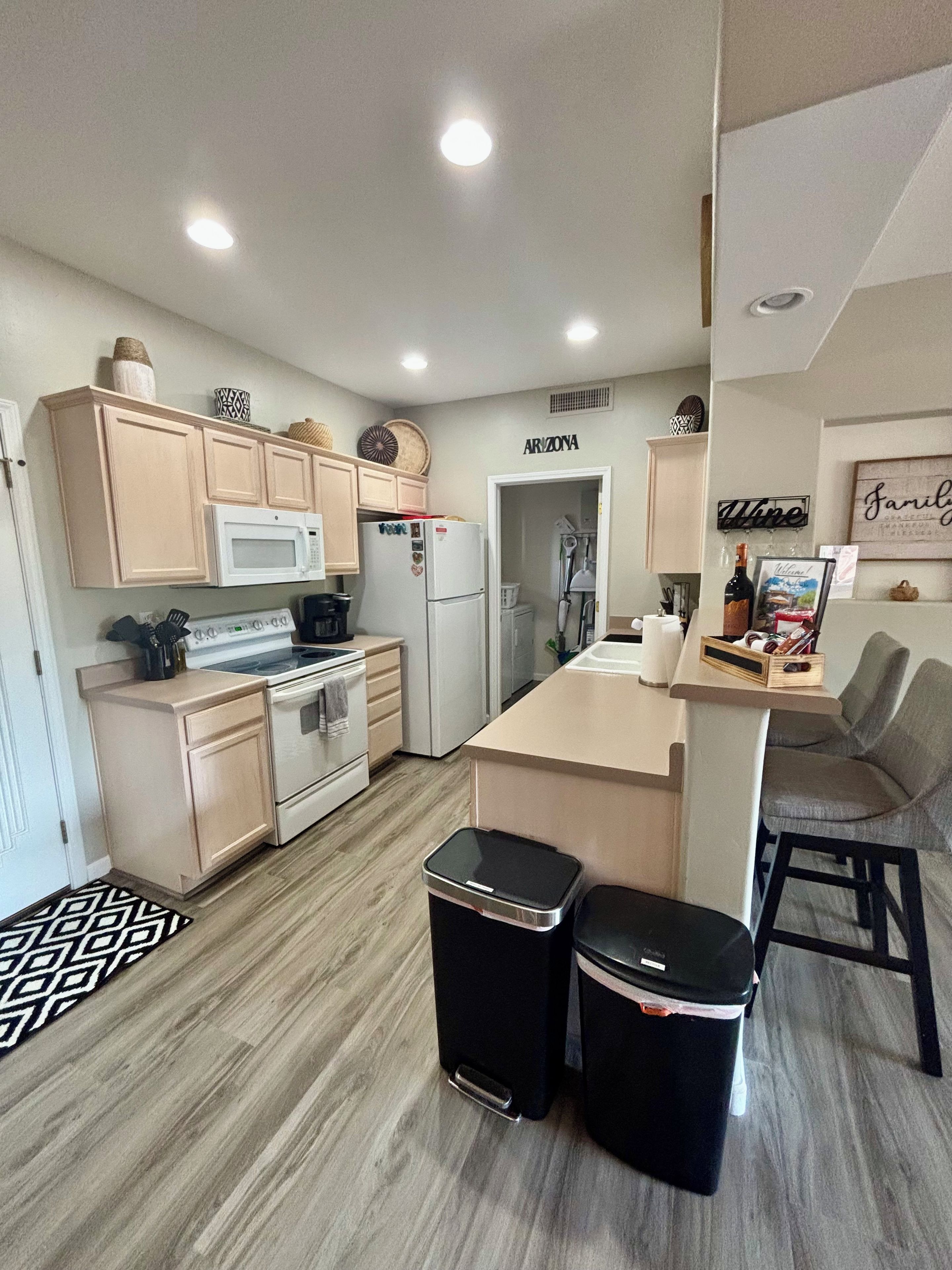 A compact kitchen with a microwave, refrigerator, and a small dining area with stools.