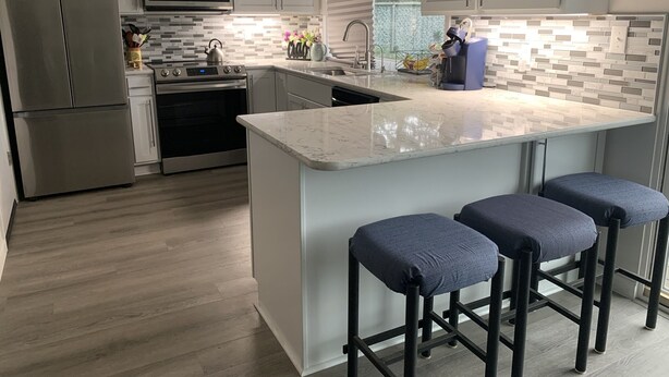 A modern kitchen with stainless steel appliances, a large island with bar stools, and a tiled backsplash. - Remote Worker? Retired? Storm Tracker? +Own Canal Dock (Ocean Shores)