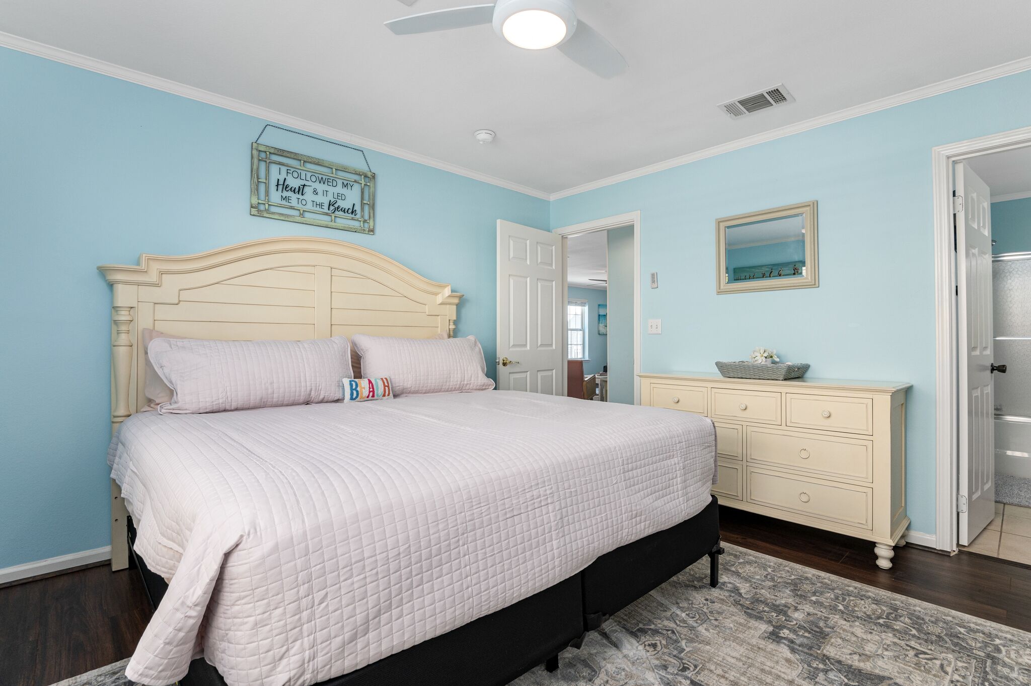 A bedroom with a bed, dresser, and a ceiling fan.