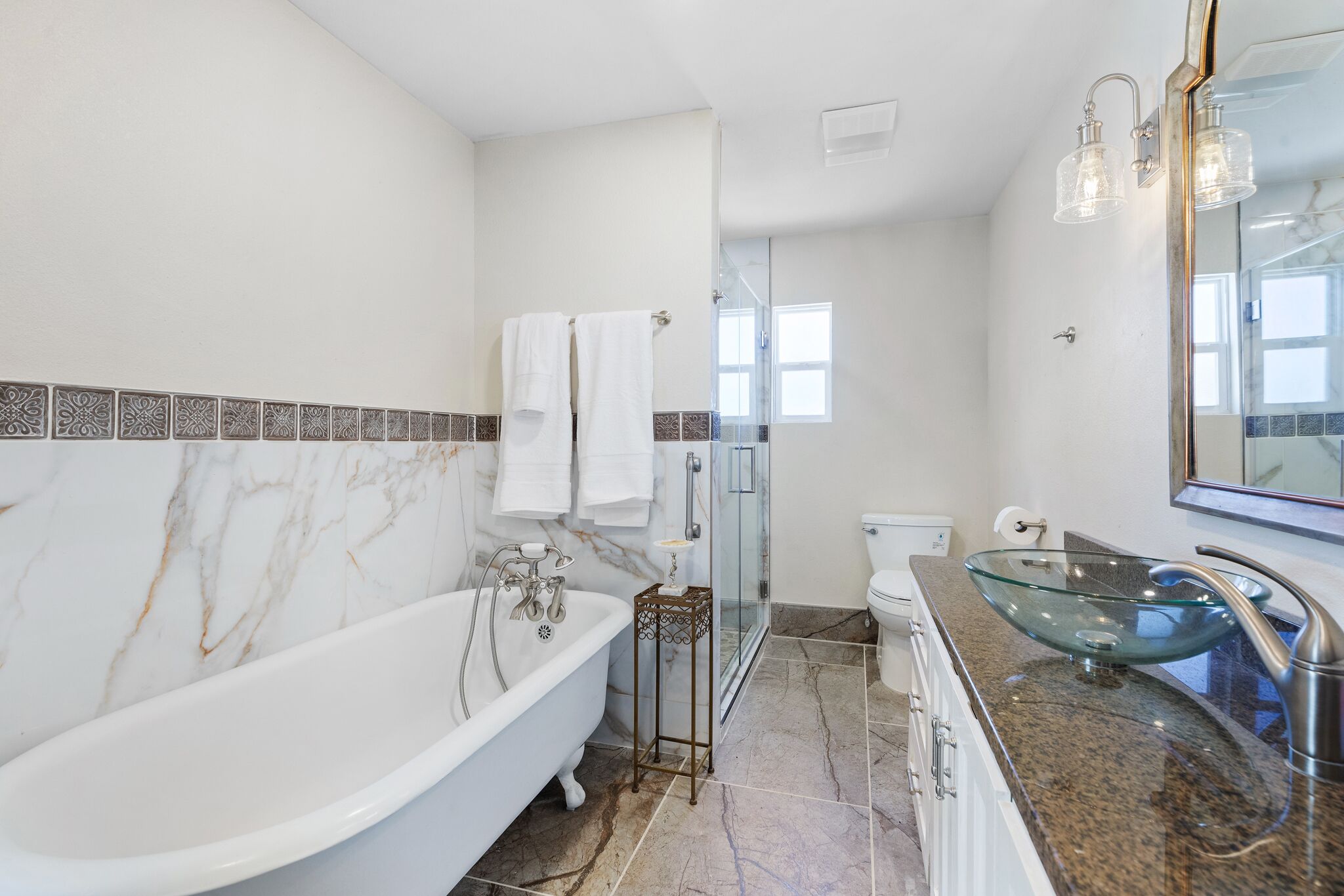Un baño moderno con una bañera independiente, un lavabo de vidrio y una ducha a ras de suelo.