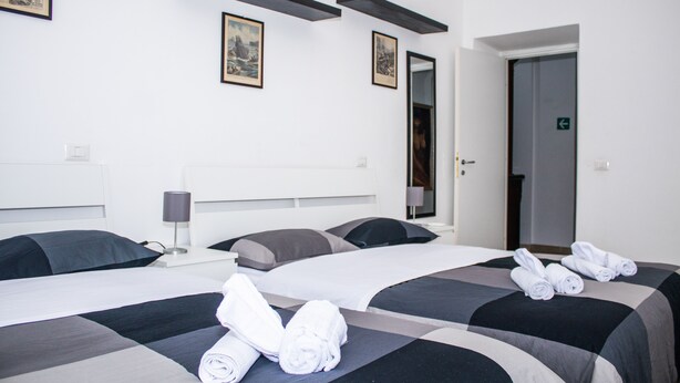 A hotel room with two beds, a flat-screen TV, a desk with a lamp, and artwork on the walls. - Gioia's House (Roma)