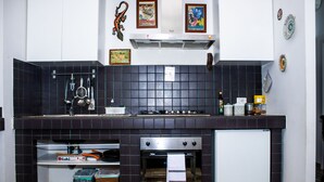 A kitchen with a gas stove, oven, and a sink. There are decorative plates on the wall and a framed picture above the stove. - Gioia's House (Roma)