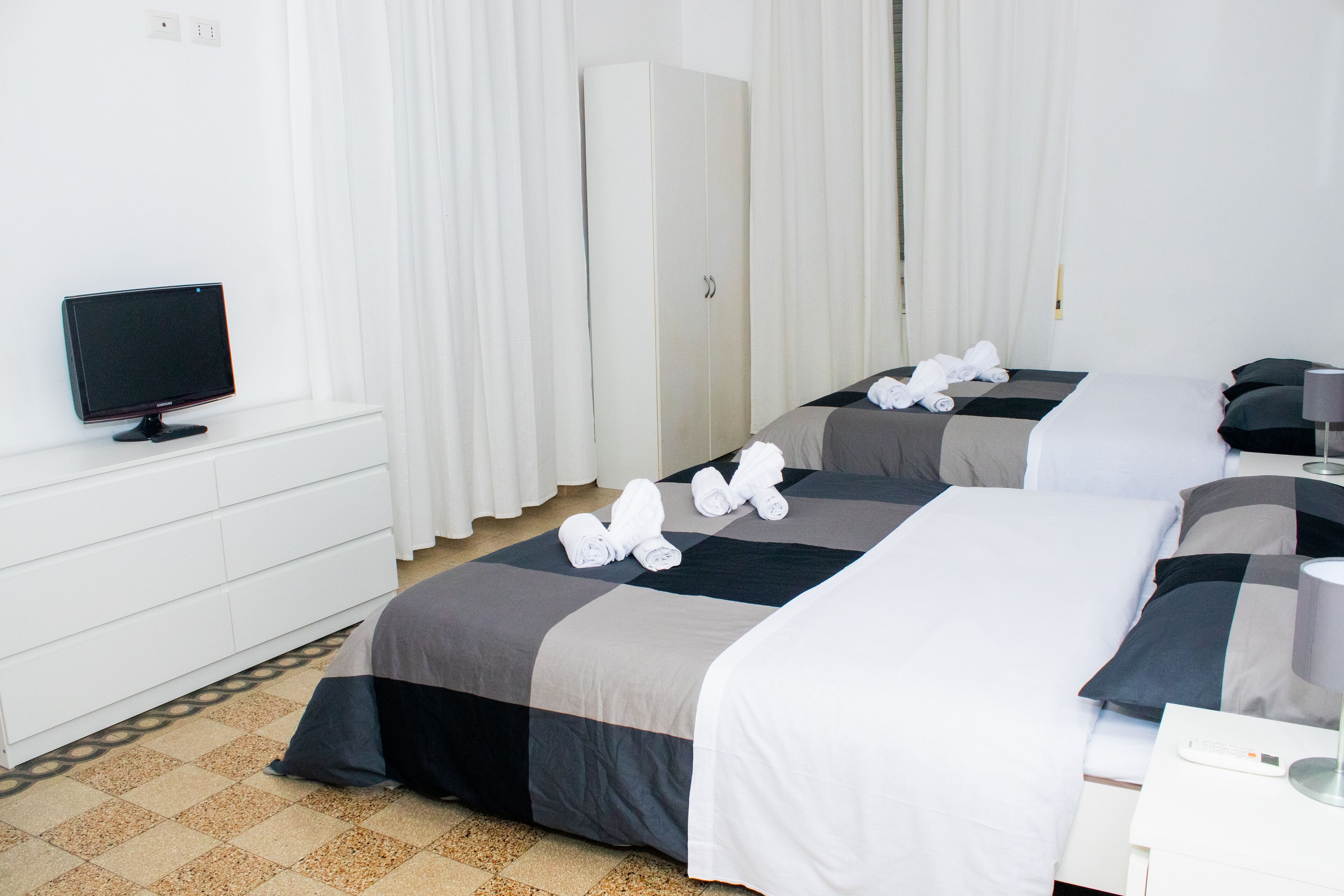 Une chambre d’hôtel avec deux lits, une télévision, une armoire et une salle de bain.