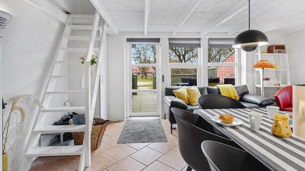 A modern kitchen with a dining area, white cabinetry, and a staircase leading to an upper level. - Beautiful home in Hemmet with WiFi (Hemmet)