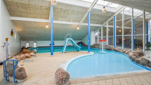 An indoor swimming pool with a slide, rock features, and a view of the outside through large windows. - Beautiful home in Hemmet with WiFi (Hemmet)
