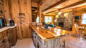 A rustic cabin interior with a wooden bar, stone fireplace, and a cozy seating area. - Great Creekside Hideaway Rustic Cabin - Secluded, Creekside Family Cabin (Topton)
