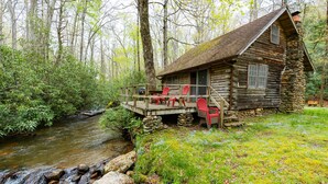A rustic log cabin with a wooden deck, a stone foundation, and a view of a flowing stream. - Great Creekside Hideaway Rustic Cabin - Secluded, Creekside Family Cabin (Topton)