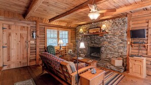 A cozy log cabin interior with a stone fireplace, wooden furniture, and a television. - Great Creekside Hideaway Rustic Cabin - Secluded, Creekside Family Cabin (Topton)