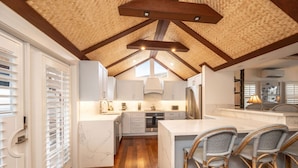 A modern kitchen with white cabinetry, a central island with bar stools, and a wooden ceiling with exposed beams. - Old Town Caribbean Estate Key West -  Great for Groups - Private Pool - Sleeps 21 (Key West)